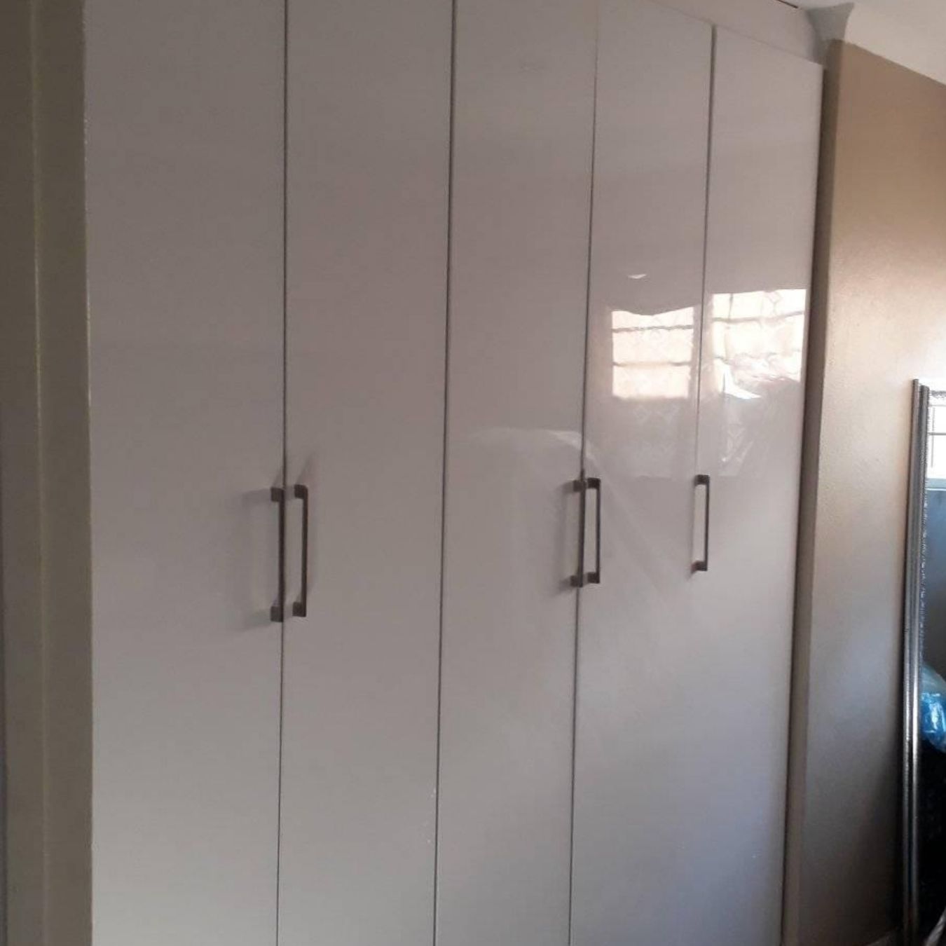 Five-door white gloss wardrobe with bar handles